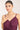 Woman wearing a purple dress and green necklace against a plain background