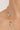 Gold necklace with green beads on a person's neck against a neutral background