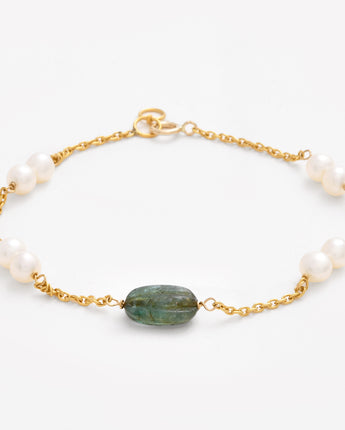 Bracelet with pearls and a green stone on a white background