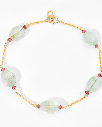 Gold bracelet with white and red beads on a white background