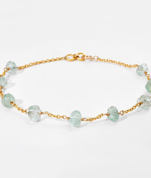 Gold bracelet with white gemstones on a light gray background
