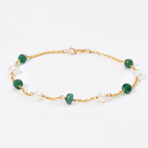 Bracelet with green gemstones and gold chain on a white background