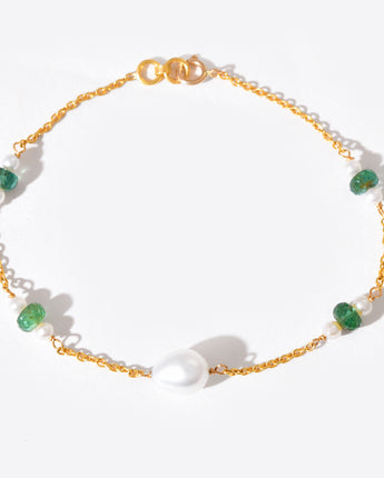 Gold bracelet with green gemstones on a white background