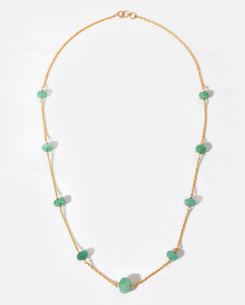 Necklace with green gemstone on a gold chain against a white background