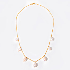 Gold necklace with pearl drops on a light background