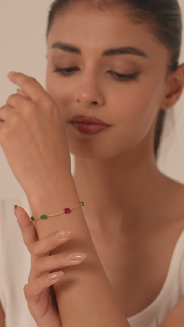 Women wearing a bracelet with green and red gemstone.