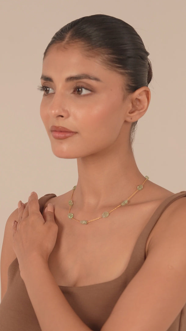 Women wearing a gold chain necklace with gemstones.
