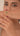 Woman showing a bracelet with red and green stones against a plain background in a video.
