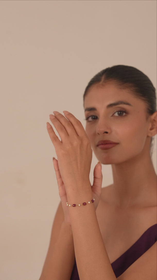 Woman wearing a gemstone and pearl bracelet in her hand.