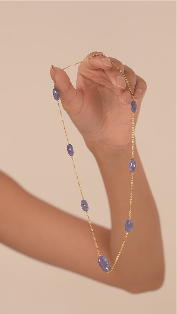 A women showing the quality of a purple gemstone necklace.