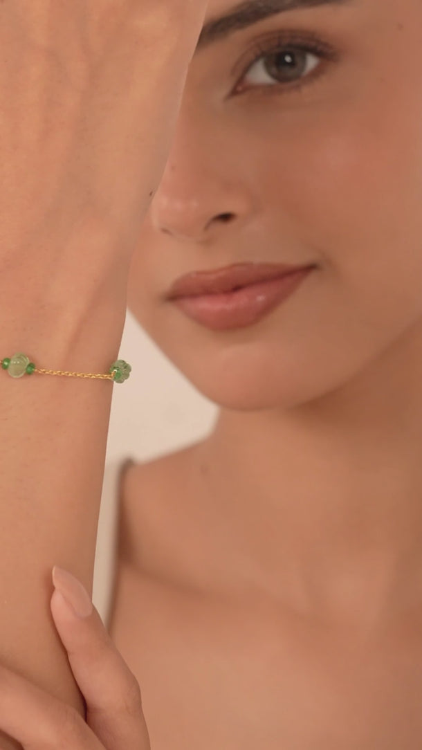Woman wearing a green gemstone bracelet in her wrist.